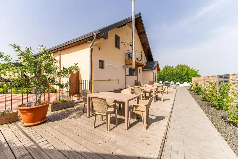 Curtea pensiunii cu oleandru înflorit și balcon la etaj